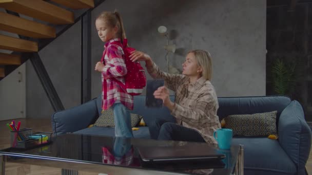 Caring mom packing backpack of cute schoolgirl — Stock Video