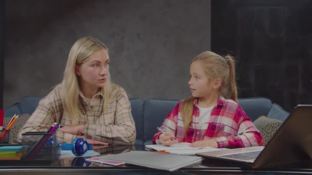 Hija inteligente explicando el trabajo escolar a la madre en casa — Vídeo de stock