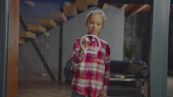 Cheerful girl drawing smiley face on window glass — Stock Video