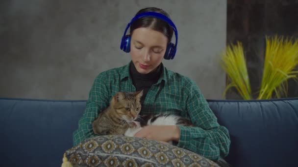 Mujer en auriculares relajante con gatos en casa — Vídeos de Stock