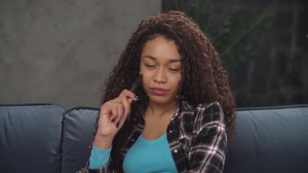 Красивая черная женщина с ручкой думает о чем-то — стоковое видео