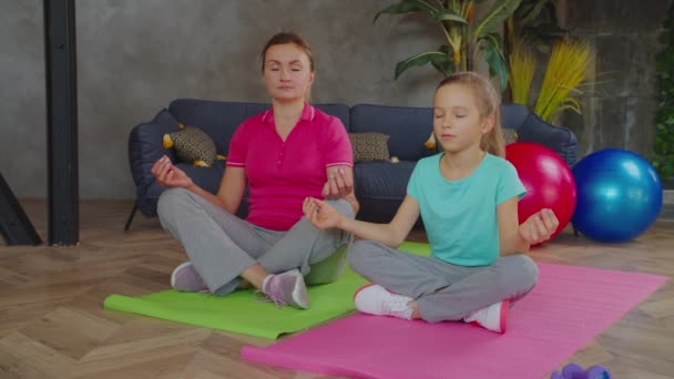 Relaxed mom and daughter meditating in lotus pose — Stock Video