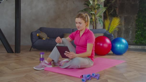 Sportieve vrouw video conferencing met fitness trainer — Stockvideo