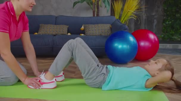 Close-up of elementary age girl doing crunches at home — Stock Video