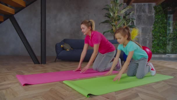 Фитнес-мама с ребенком, выполняющим упражнения на доске в помещении — стоковое видео