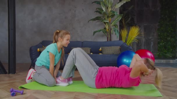 Активная фитнес-мама делает приседания с помощью дочери — стоковое видео
