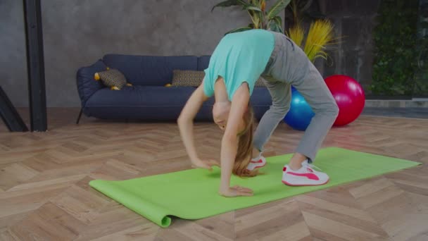 Гімнастична дівчина виконує мостову позу в приміщенні — стокове відео