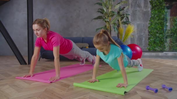 Αθλητική τακτοποίηση μαμά και κορίτσι κάνει push ups μαζί στο σπίτι — Αρχείο Βίντεο