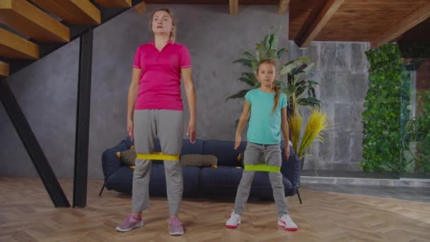 Sporty fit mom and child doing banded squat indoors — Stock Video