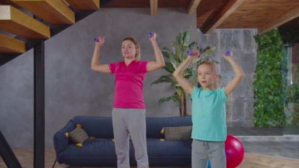 Mamá y su hija haciendo ejercicio con pesas en casa — Vídeos de Stock