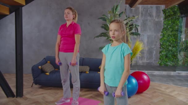 Mother and child doing dumbbell upright row indoors — Stock Video