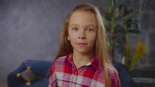 Spitzbübisch kleines Mädchen macht lustige Gesichter drinnen — Stockvideo