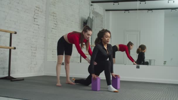 Sportig passform svart kvinna stretching med tränare inomhus — Stockvideo
