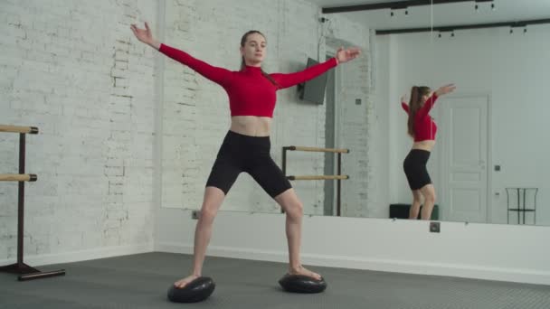 Fit kobieta robi crossover plie squat na poduszkach równowagi — Wideo stockowe