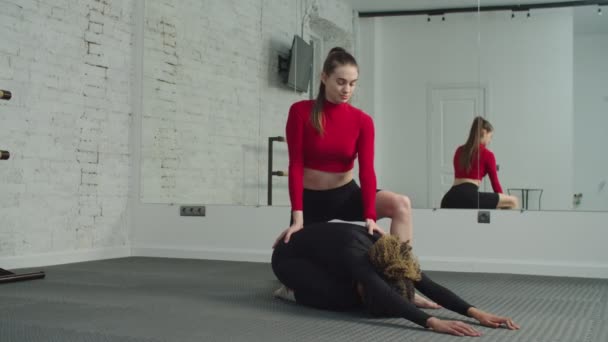 Mujer en forma relajada haciendo yoga pose infantil con entrenador — Vídeos de Stock