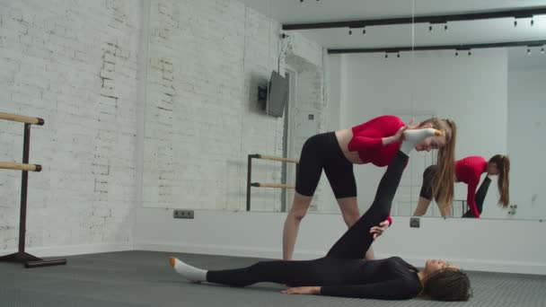 Adatta donna che fa esercizi di stretching con l'aiuto dell'allenatore — Video Stock