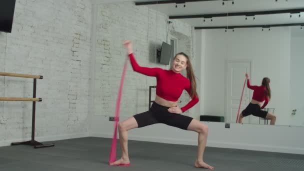 Mujer en forma activa haciendo sentadilla de sumo con bandas en el gimnasio — Vídeos de Stock