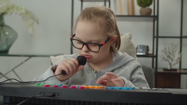 Позитивная маленькая девочка играет на синтезаторе дома — стоковое видео