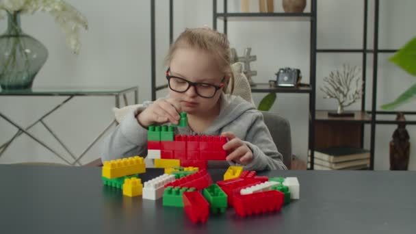 Down sendromlu küçük kız oyuncak bloklarıyla oynuyor. — Stok video