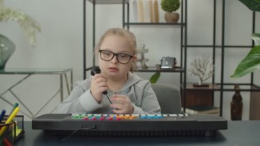 Sentezleyiciyle oynayan neşeli Down Sendromlu çocuk