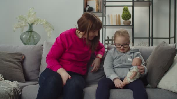 Amante mãe e menina com síndrome de down conversando no sofá — Vídeo de Stock