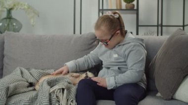 Engelli sevimli çocuk. Kanepede köpekle bağ kuruyor.