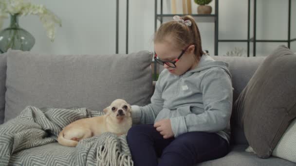 Ragazza allegra con sindrome di Down rilassante con animale domestico al coperto — Video Stock