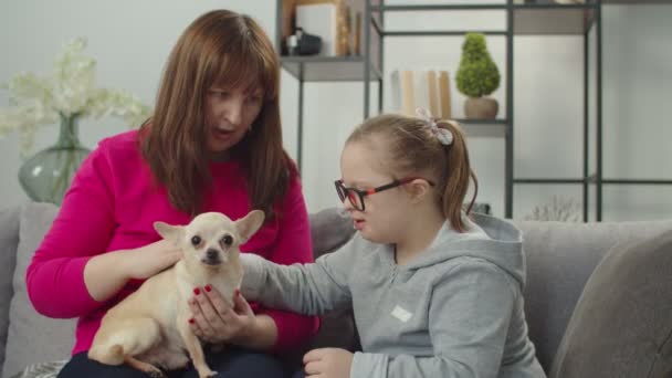 Carino figlia con malattia genetica, mamma e cane relax sul divano — Video Stock