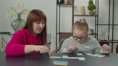 Down sendromlu kız ve annesi eğitim oyunu oynuyorlar.