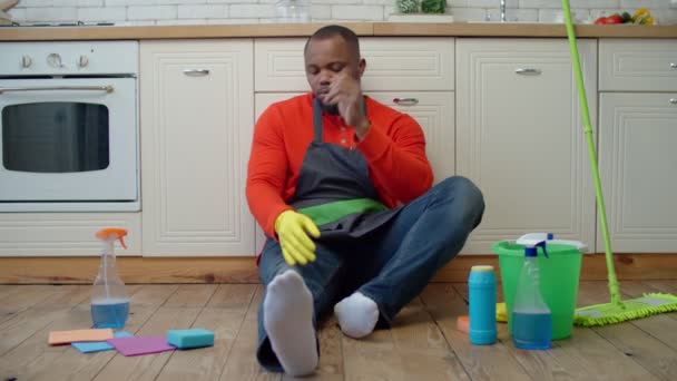 Измученный африканский американец отдыхает после уборки. — стоковое видео