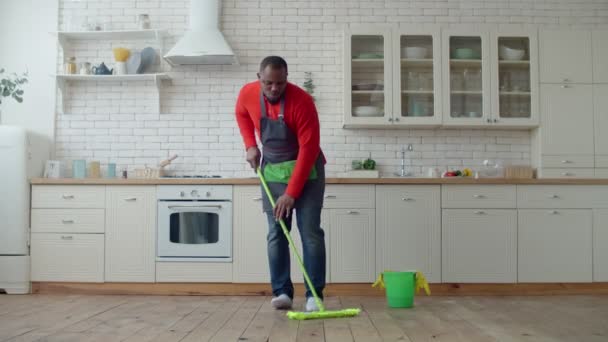 Optimistisk svart man som dansar med mopp under städningen — Stockvideo