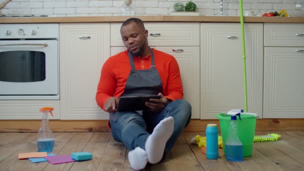 Yorgun adam temizlikten sonra tablet bilgisayarda geziniyor — Stok video