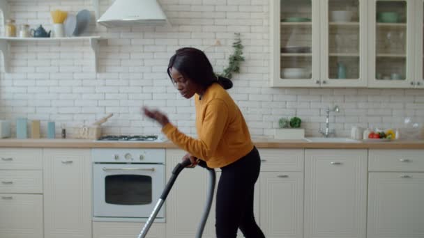 负责任的勤劳迷人的非洲少女形象美国少女吸尘地板与胡佛 做计划中的一般房屋清洁 同时在家里做家务活 — 图库视频影像