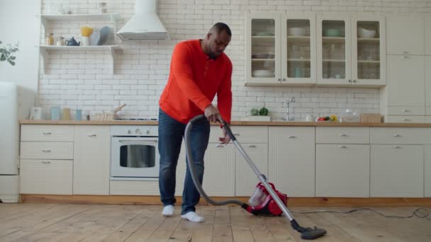 Ernstige Afrikaanse man schoonmaken vloer met stofzuiger — Stockvideo