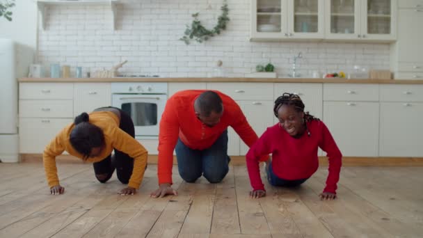 Família africana unida fazendo flexões juntas na cozinha — Vídeo de Stock