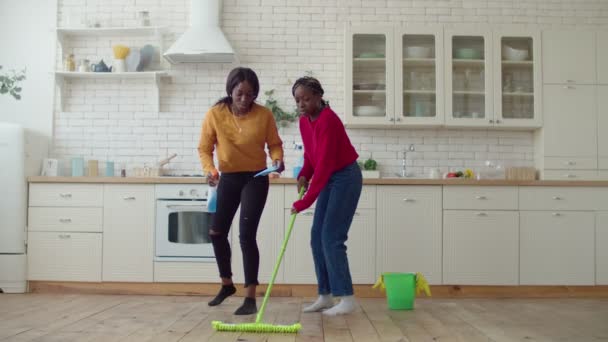Meninas adolescentes alegres dançando com suprimentos de limpeza durante a limpeza — Vídeo de Stock