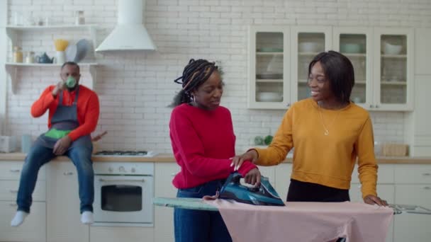 Siyah genç kızlar babalarına çamaşır ütülemede yardım ediyor. — Stok video