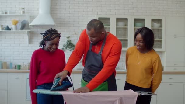 Verzorgende zwart vader onderwijs schattig tiener dochters strijken — Stockvideo