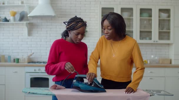 Limpeza preto adolescente irmãs inclinado para uso de ferro — Vídeo de Stock