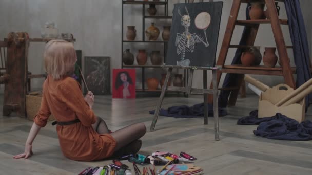 Творча жінка-художник дивиться на живопис в художній студії — стокове відео