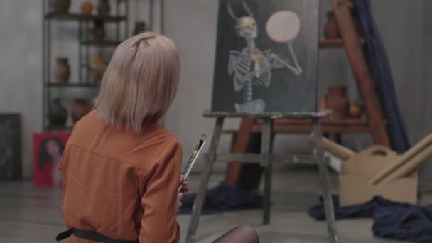 Rear view of woman painter admiring painting indoors — Stock Video