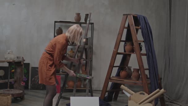 Peintre femelle ajustant la hauteur du chevalet dans un atelier d'art — Video