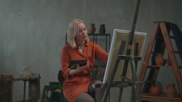 Pintora femenina redibujando la imagen de la tableta PC al caballete. — Vídeo de stock