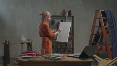 Kadın sanatçı atölyede online sanat dersi veriyor.
