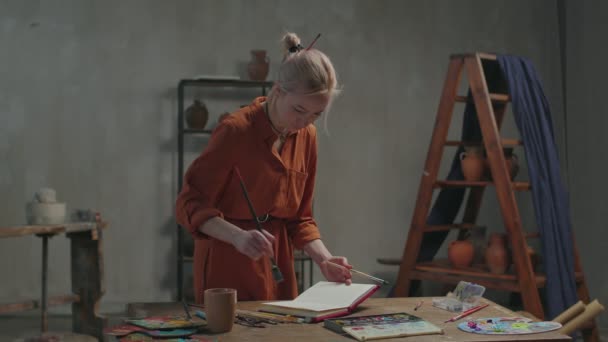 Kvinnlig målare ritar i skissbok med akvareller — Stockvideo