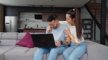 Asyalı çiftler evlerinde dizüstü bilgisayarda geziniyorlar.