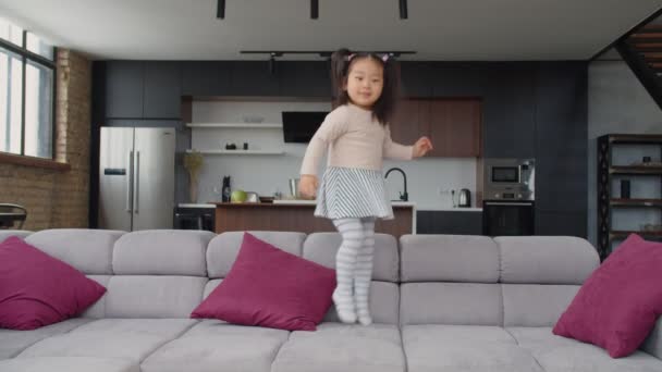Entusiasmado bonito asiático criança menina saltando no sofá — Vídeo de Stock