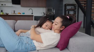Mutlu Asyalı anne ve yeni yürümeye başlayan kız birbirlerini kucaklıyorlar.