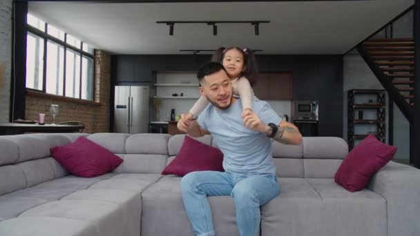 Happy asian dad and toddler daughter having fun on sofa — Stock Video