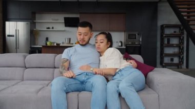 Sevgi dolu Asyalı çift evdeki kanepede sarılıyor..